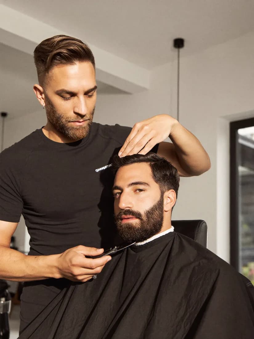 Barbiere rifinisce la barba di un cliente